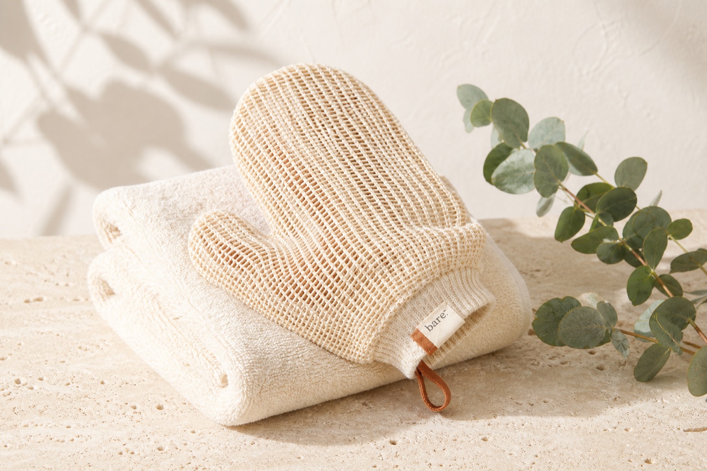 bare. the mitt — reusable cream open-weave plant-fiber scrub mitt on a folded towel